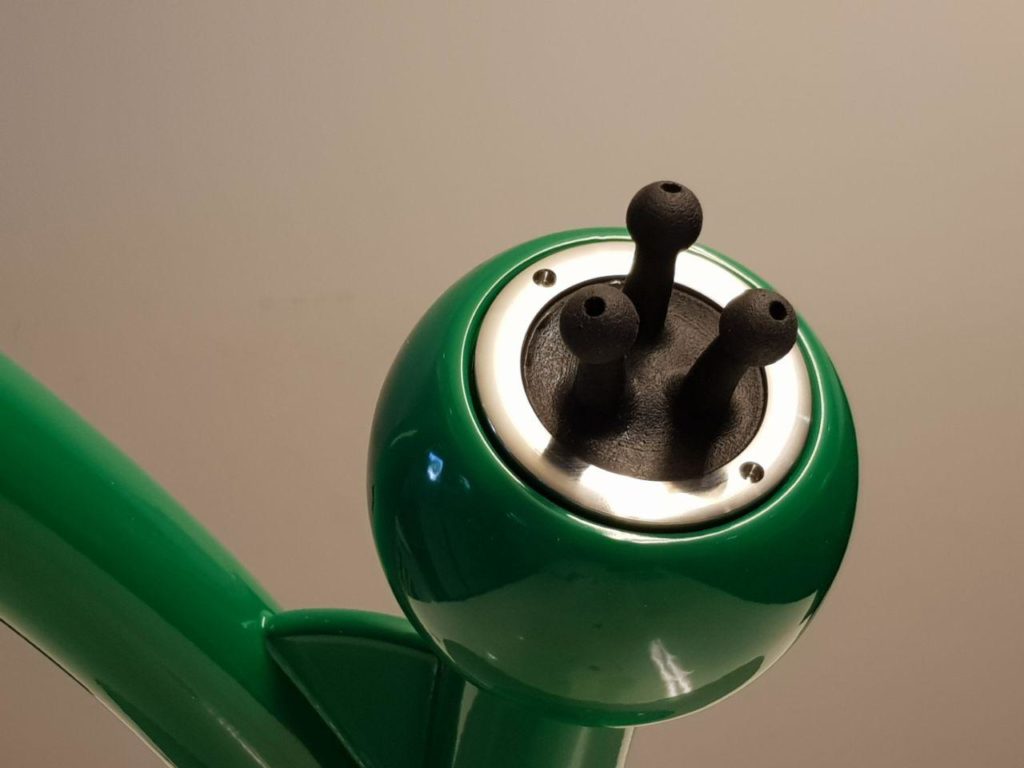 Dune grasses: North Sea feeling at the children's pool ROIGK Nahaufnahme eines grünen Kinderbeckens mit einem glänzenden Metallrand und drei schwarzen Gummitüllen, die aus der Oberseite herausragen, vor einem einfarbig beigen Hintergrund.