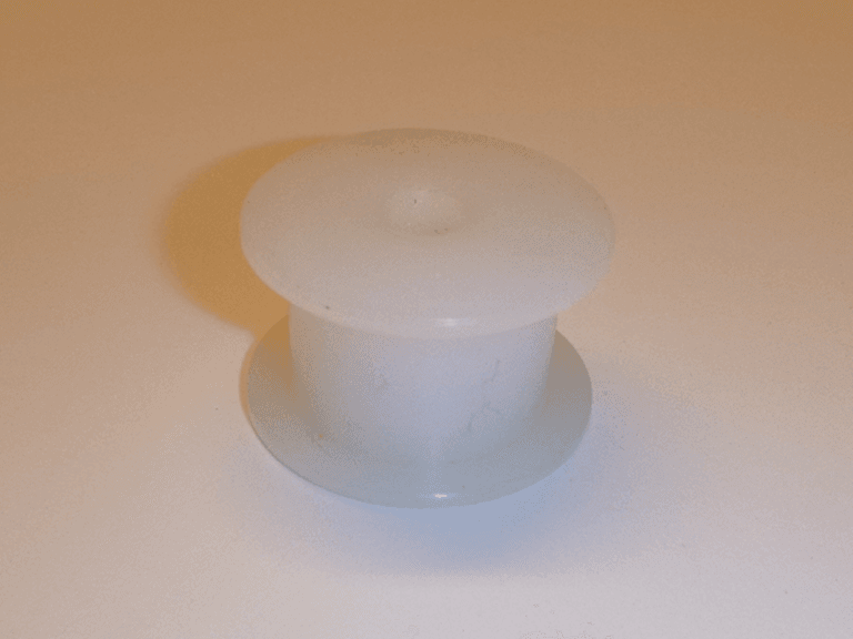 Eine kleine, weiße, zylindrische E# Spannrolle R771252-24 (für Walzenverstellung) aus Kunststoff mit Flanschen an beiden Enden wird auf eine glatte, helle Fläche gelegt und wirft einen weichen Schatten nach links.