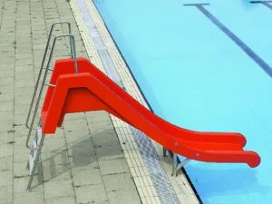 Die Wasserrutsche R152-1.1, eine leuchtend rote Rutsche mit Metallstufen, befindet sich am Rande eines Außenbeckens und endet knapp über dem Wasser, so dass man sowohl das Becken als auch das umliegende geflieste Deck sehen kann.